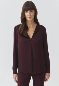 Bordo bluza dugih rukava s V-izrezom i opuštenim krojem. Mekana tkanina, minimalni detalji šivanja i manšete na gumb. Jednostavan i klasičan dizajn.