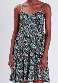 Robe noire à bretelles spaghetti réglables, ornée d'un motif de feuilles vertes et brunes, coupe ample et jupe à volants.