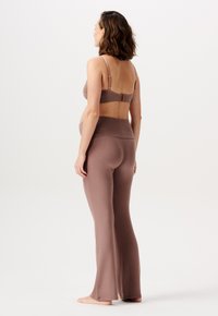 Brun sømløs bh og flagrende leggings, lavet af blødt stof. Leggings har en høj talje, mens bh'en har justerbare stropper og en hægtslås.