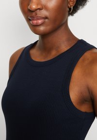 Navy blau gerippter Tanktop mit rundem Ausschnitt und weiten Armlöchern, aus einem glatten Stoff gefertigt, mit einer figurbetonten Silhouette und subtiler Textur.