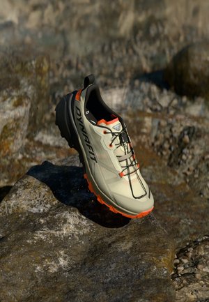 Ľahká šedá bežecká obuv s čiernymi akcentmi a oranžovou podrážkou. Vlastnosti zahŕňajú sieťový zvršok a bezpečný systém šnurovania pre stabilitu.