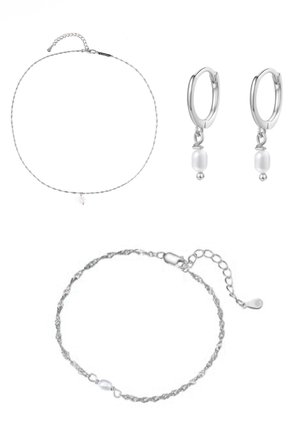 Zarter silberner Kettenarmband mit einer kleinen Perle am Handgelenk, gezeigt von einer Hand mit hellbeigen lackierten Nägeln.