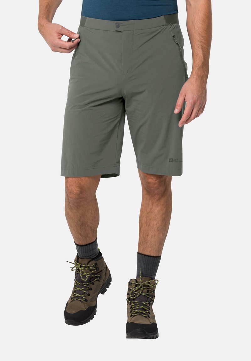 Shorts de randonnée gris en tissu léger, dotés d'une fermeture à bouton, d'une poche zippée et d'une coupe décontractée, associés à des chaussures de randonnée marron.