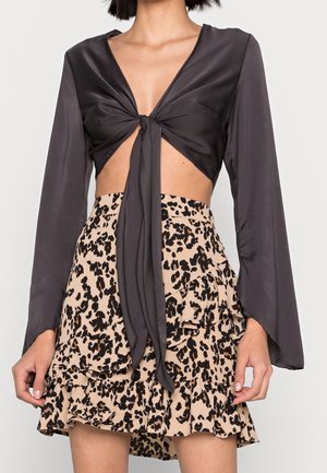 Black satin cropped top with long, bell sleeves and front tie detail, paired with a beige leopard print ruffled skirt.