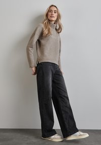 Vaaleanharmaa ribatattu poolopaita, mustat leveälahkeiset farkut ja beige kengät, joissa on yksityiskohtia. Slim fit, pehmeä rakenne ja jännittävä muotoilu.