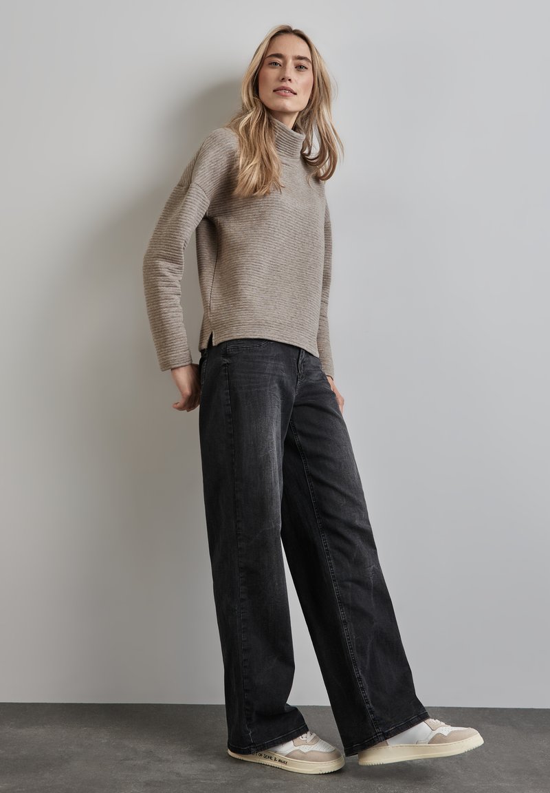 Vaaleanharmaa ribatattu poolopaita, mustat leveälahkeiset farkut ja beige kengät, joissa on yksityiskohtia. Slim fit, pehmeä rakenne ja jännittävä muotoilu.