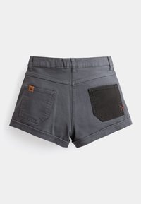 Shorts en denim gris avec une poche arrière ornée d'un patch en tissu noir et de détails en surpiqûre rouge. Ourlet roulé et taille standard.