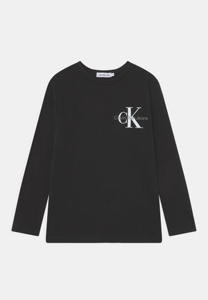 Czarna koszulka z długim rękawem i okrągłym dekoltem z białym logo "CK Calvin Klein Jeans" po lewej stronie klatki piersiowej.