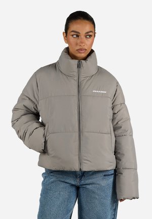 Grå pufferjakke med høy krage, glidelås foran og oversized passform. Har sydd paneler og hvit logo på brystet. Glatt, blank tekstur.