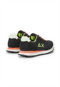 Scarpe sportive in suede nere con accenti verde neon, suola arancione e lacci con motivo, dettagli del logo geometrico sui lati.