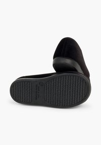 Scarpe slip-on in suede nero con suola in gomma texturizzata, dotate di un design curvo e cuciture minime sulla parte superiore.