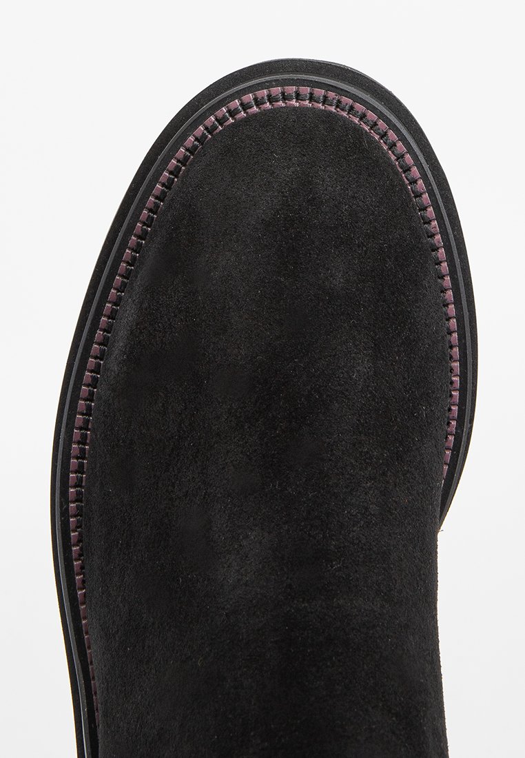Stivaletto in suede nero con punta arrotondata, cuciture a contrasto in viola lungo il bordo e suola in gomma testurizzata.