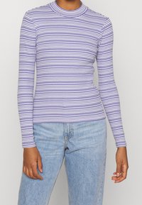 Pruhovaný dlouhý rukáv top v světle fialové a bílé barvě, se stojáčkem a přiléhavým střihem, vyrobený z jemného žebrovaného materiálu.