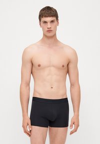 Schwarze Boxerbriefs aus Bio-Baumwolle mit einem weichen Bund, der mit dem Branding "Organic Basics" versehen ist. Glatte Textur mit einer figurbetonten Passform.