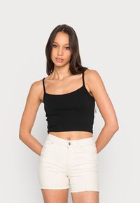 Top cropped preto com alças finas, apresentando um design ajustado. Combinado com calções de ganga marfim, exibindo uma bainha desfiada e estilo de cinco bolsos.