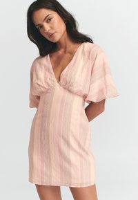 Abito rosa chiaro con maniche a farfalla corte, scollatura a V e strisce verticali in vari colori. Tessuto morbido e texturizzato con una silhouette aderente.