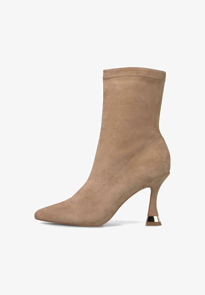 Beige suède enkelboot met spitse neus, slanke mid-hoge gebogen hak en metallic accent aan de basis van de hak.
