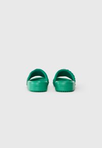 Sandali verde in plastica con materiale liscia, apertura sul retro e cinturini ritagliati. La suola è texture per una migliore aderenza, con un design piatto.