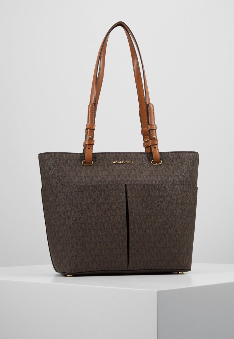 Sac cabas monogramme marron en matériau synthétique texturé. Doté de deux bretelles, d'une fermeture éclair supérieure et de deux poches avant ouvertes.