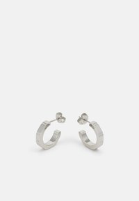 Pendientes aros de metal plateado con un diseño texturizado, que cuentan con un pequeño respaldo de clip y una marca en uno de los aros. Forma redondeada con un acabado pulido.