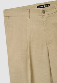 Pantaloni formali beige con chiusura con bottone, passanti per cintura ed etichetta della taglia che mostra IT 46, USA 31, EU 42 del marchio Terranova.