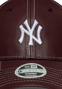 Burgunderfarbenes Leder-Cap mit einem weißen gestickten "NY"-Logo. Verfügt über weiße Nähte und einen verstellbaren Riemen. Mit New Era 9FORTY-Etikett versehen.