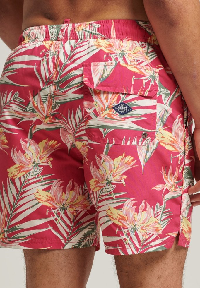 Bañador corto de tejido ligero, con una base rosa y un patrón floral tropical, bolsillo lateral y cintura elástica para mayor comodidad.