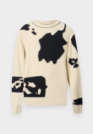 Hosszú ujjú, krémszínű kötött pulóver szabálytalan nagy fekete absztrakt foltokkal elöl és az ujjakon szétszórva.