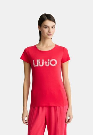 T-shirt in cotone rosso con maniche corte, caratterizzato dal logo "LIU·JO" in bianco. Presenta un colletto tondo ed è indossato con pantaloni rossi abbinati.