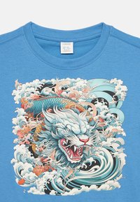 Μπλε βαμβακερό t-shirt με πολύχρωμο σχέδιο εμπνευσμένο από την Ασία, που απεικονίζει έναν βρυχώμενο δράκο ανάμεσα σε στυλιζαρισμένα κύματα και σύννεφα.