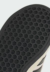 Gummisulor med ett svart hexagontal mönster, med upphöjda texturer för grepp. Ljust färgade kanter kontrasterar med den svarta basen.
