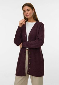 Cardigan en tricot bordeaux avec un col en V, tissu texturé et six boutons marron sur le devant. Coupe légèrement plus longue avec fentes sur les côtés.