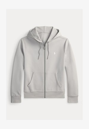 Gaiši pelēka zip-up kapuce, izgatavota no mīkstas auduma, ar regulējamu kapuci, divām priekšējām kabatām un mazu logo uz krūtīm.
