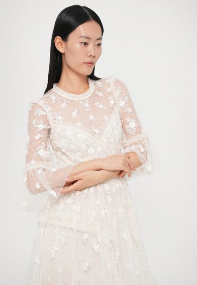 Rochie ușoară, transparentă, cu modele florale brodate și detalii cu paiete. Are guler cu volane și mâneci evazate din țesătură alb-crem.