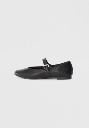 Black leather Mary Jane flat shoe with a rounded toe, adjustable strap, and small silver buckle detail, featuring a low heel and smooth finish.