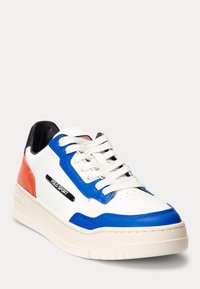 Zapatilla blanca con acentos en azul y naranja, con un acabado texturizado, punta redonda, cuello acolchado y cordones blancos. Detalle del logo en negro presente.