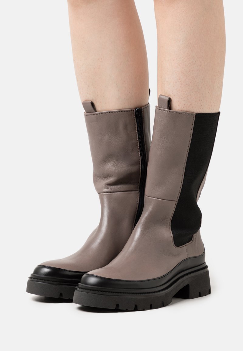 Botas de cuero gris hasta el tobillo con paneles elásticos negros, cremallera lateral y una suela gruesa negra. Textura suave y altura hasta la mitad de la pantorrilla.