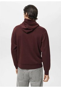 Bordo kapuca s sproščeno prileganjem, ki vsebuje prostorno kapuco, rebraste manšete in rob. Tkanina je gladka z minimalno vidnimi šivi.