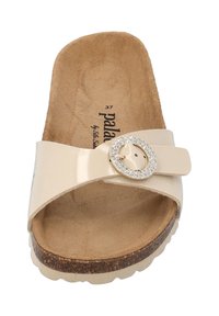 Beige schuif sandaal met een glanzende afwerking, verstelbare band met een fonkelende ronde gesp, kurkachtige zool en zachte suede binnenzool.