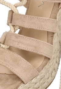 Sandalia de cuña de ante beige con suela de yute trenzado, que presenta cuatro correas horizontales y un forro interior suave.