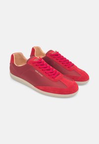 Rote Sneaker aus Wildleder und Textil mit flachen Schnürsenkeln, gepolstertem Kragen und einer strukturierten Gummisohle, ausgestattet mit einem dezenten Logodetail.