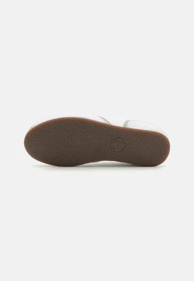 Zapato blanco con una suela de goma texturizada. La suela exterior es de color marrón, con un detalle de logo circular cerca del centro. Diseño simple y funcional.
