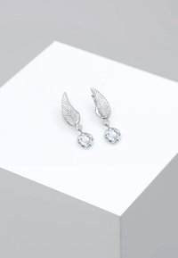 Silberne flügelförmige Ohrringe mit einem blauen Kristallanhänger. Ausführliche Flügeltextur mit einer runden Edelsteineinfassung.