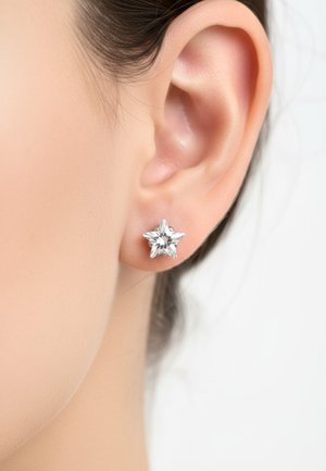 Star-shaped stud earring in silver-tone metal with clear gemstone accents. The design features sharp points and a polished finish.