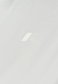 Tessuto bianco con un delicato design a logo in rilievo caratterizzato da linee angolari. La texture appare liscia e uniforme, senza motivi distinti.