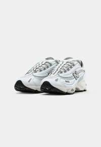 Hvide atletiske sneakers med grå accenter, mesh-overdel, tekstureret design, rund tåkonstruktion, sikker snøresystem, og mønstret sort gummisål.