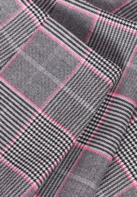 Svart och vit rutig tyg med rosa accentlinjer. Slät textur med en blandning av små och stora rutor i ett geometriskt mönster.