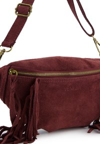 Bordeauxkleurige suède crossbodytas met een ritssluiting aan de voorkant, franjes en een verstelbare band met goudkleurige details.