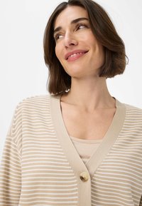Beige- und weiß gestreifter Cardigan mit V-Ausschnitt und einem einzelnen runden Knopf vorne. Weiche Textur und leichtes Design.