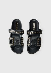 Μαύρα σανδάλια τύπου σλάιντ από συνθετικό δέρμα με χρυσά μεταλλικά στοιχεία, δύο λουριά με κυκλικές περικοπές και έντονη λογότυπη λεπτομέρεια.